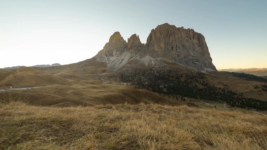 A time-lapse captures the golden hour sunset over the stunning Sassolungo mountain group in the Italian Dolomites