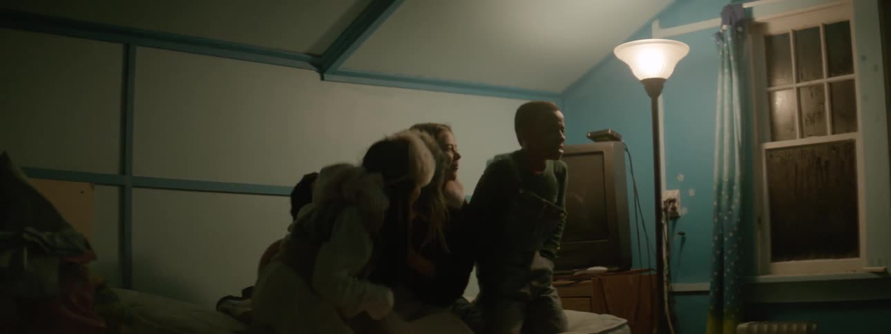 People bounce on a twin bed in a blue painted room