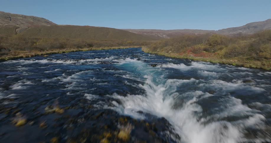 A stunning aerial view flies over the vibrant turquoise waters of the Bruarfoss waterfall in Iceland