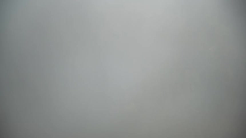 A time-lapse of dense fog completely obscuring the unique earth pyramid rock formations on a forested mountainside