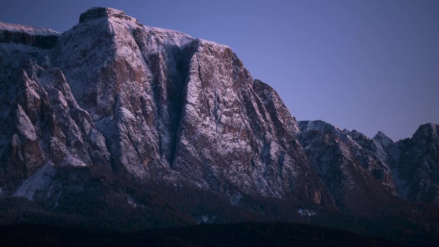Stunning timelapse captures the transition from a golden sunset casting its last light on a snowy mountain peak to a clear, starry night sky