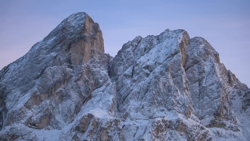 A stunning timelapse captures the transition from dusk to night over a magnificent snow-covered mountain peak