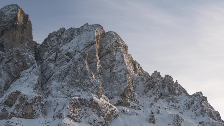 A time-lapse of majestic, snow-covered mountain peaks as clouds drift by in the crisp morning light