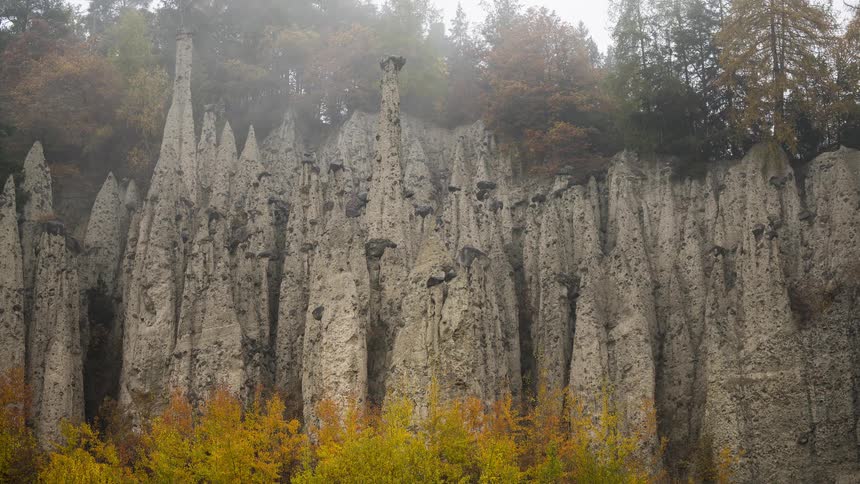 The famous Earth Pyramids of Ritten are shrouded in thick fog during a moody autumn day in South Tyrol, Italy