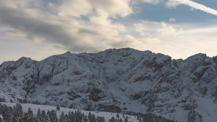 A sweeping panoramic view of a vast, snow-covered mountain landscape on a cold winter day
