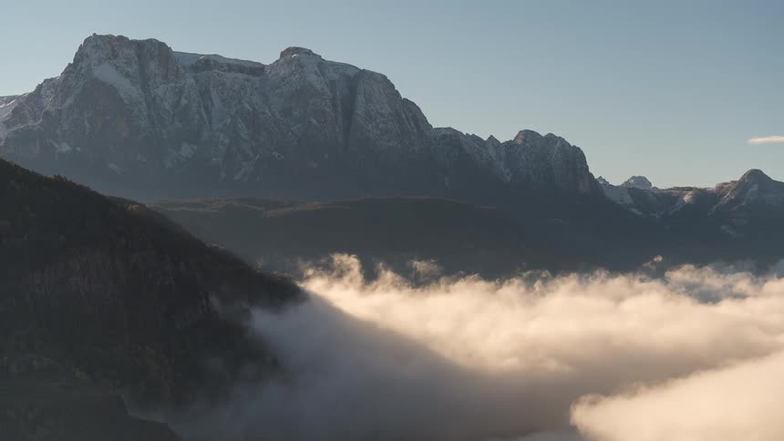 A stunning timelapse shows a sea of clouds flowing through a valley beneath the majestic snow-capped Schlern mountain in the Dolomites