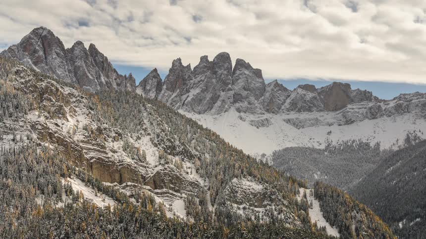 Time-lapse of clouds sweeping across the majestic, snow-covered peaks of the Dolomites mountains in winter