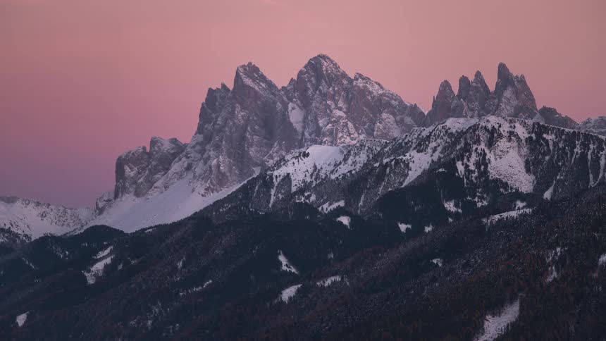 A beautiful sunset timelapse shows the alpenglow on the snowy peaks of the Italian Dolomites as the sky turns from orange to purple