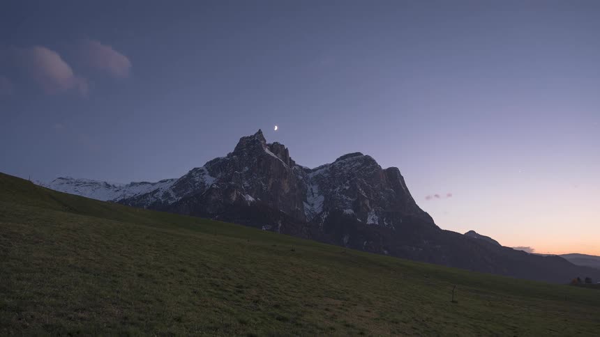 A scenic day-to-night timelapse shows the moon and stars rising over a majestic snow-capped mountain