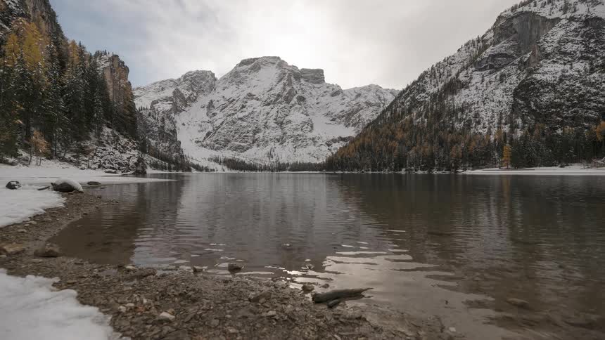 Snowy mountains are reflected in the calm waters of a pristine alpine lake during winter