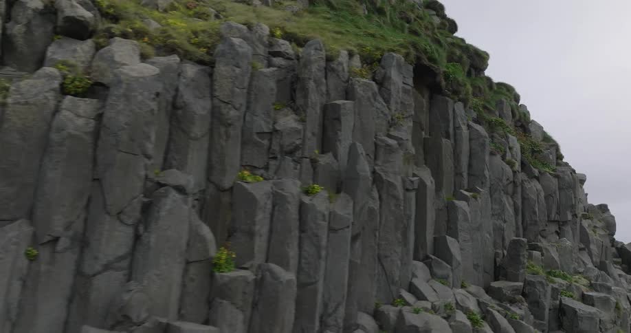 A slow cinematic pan across the rugged and geometric basalt column formations of a cliffside in Iceland