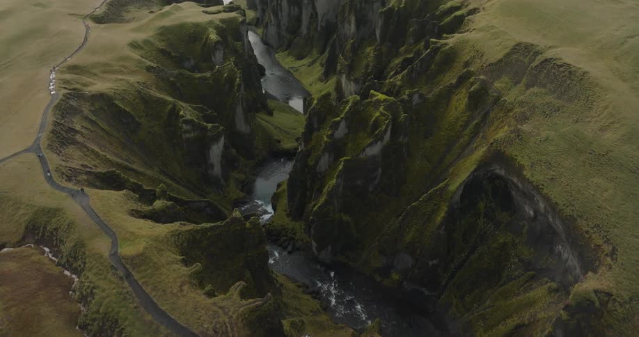 A majestic aerial view reveals the deep, moss-covered Fjaðrárgljúfur canyon with a river winding through its dramatic landscape