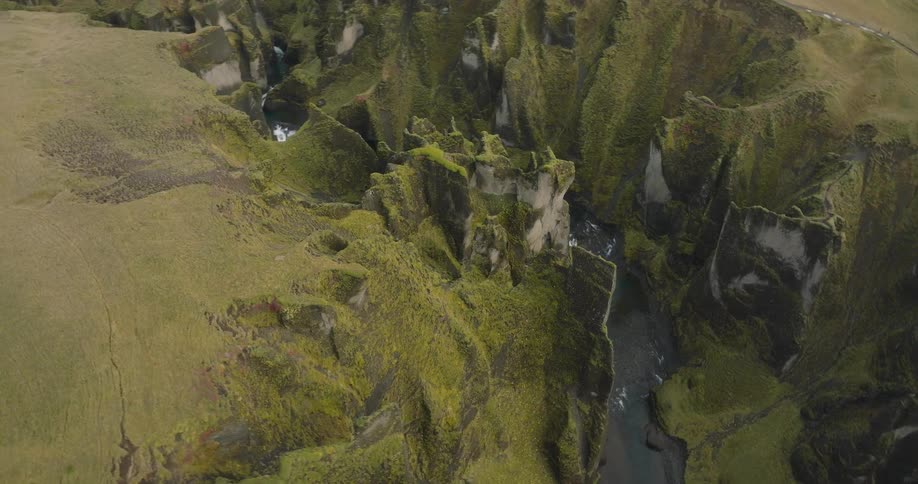 Drone footage slowly ascends over the breathtaking and ancient Fjadrargljufur canyon in southern Iceland, showcasing its dramatic cliffs and winding river