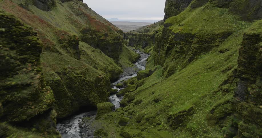 An aerial journey through a majestic and lush green canyon as a river flows through the rocky valley below