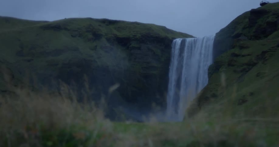 The powerful Skógafoss waterfall in Iceland tumbles down a green, misty cliffside on an overcast day