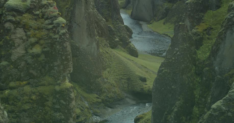 A majestic river winds its way through a deep, moss-covered canyon in the stunning Icelandic highlands