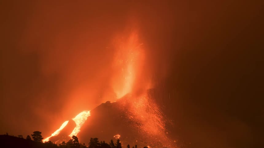 A powerful nighttime volcanic eruption spews fiery fountains of lava and thick smoke into the sky as molten rock flows down the mountainside