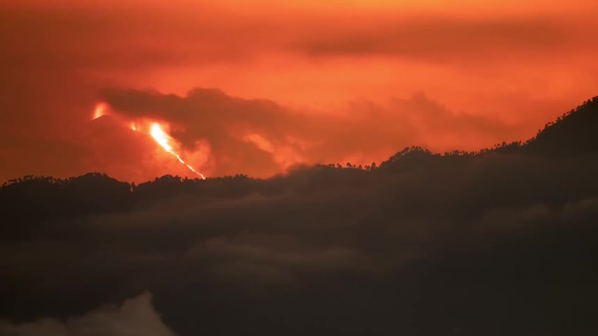 A fiery orange sunset timelapse over a mountain range as a sea of clouds and light pillars fill the sky
