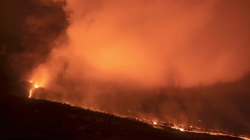 Terrifying nighttime volcanic eruption sends rivers of lava down a mountain as a colossal plume of smoke glows an ominous red