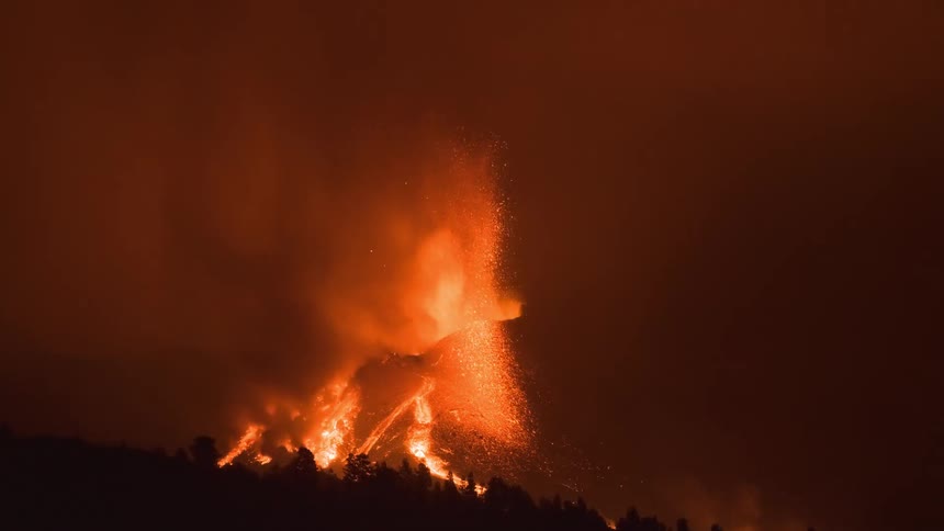 A powerful volcanic eruption at night spews fiery fountains of lava and ash into the thick, smoky sky