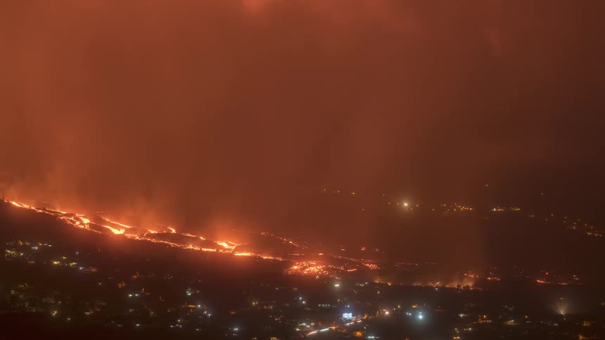 A terrifying timelapse shows a volcanic eruption at night, with rivers of lava flowing towards a city while fiery tornadoes of smoke and ash dance in the red sky