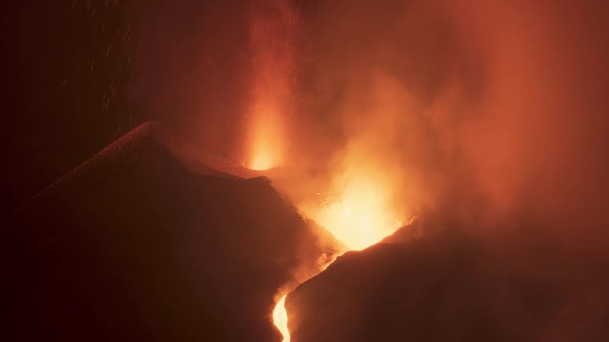 Intense close-up of a volcano erupting at night, with fiery explosions and lava flows illuminating the billowing smoke