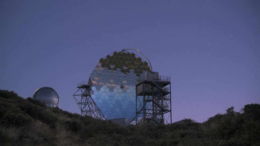 A time-lapse of the MAGIC telescope at Roque de los Muchachos Observatory transitioning from a purple twilight to a star-filled night sky