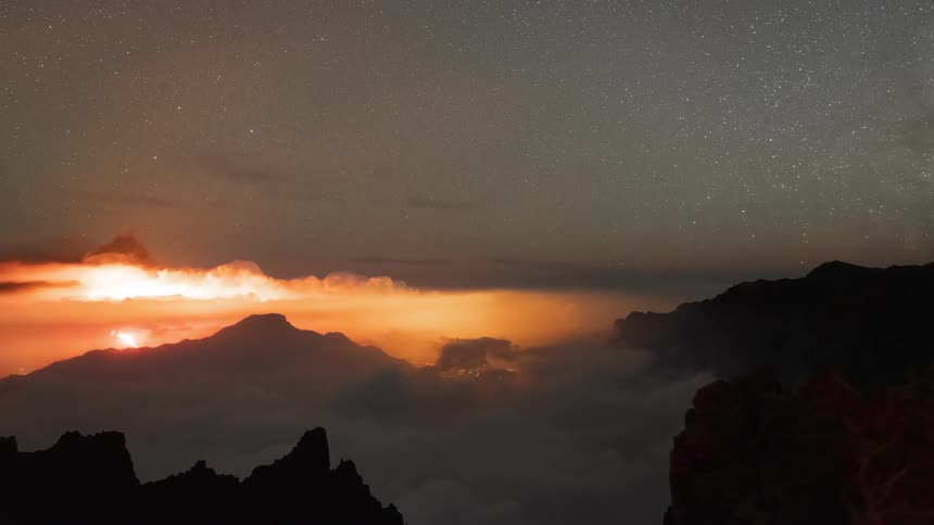 A stunning time-lapse of a volcano erupting at night under a star-filled sky as the moon sets over the mountains