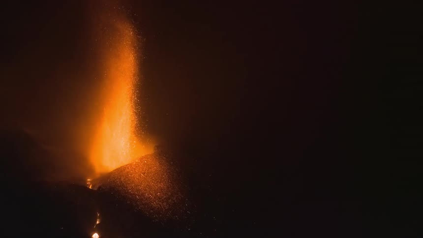 A powerful volcanic eruption illuminates the night sky as fiery lava and ash spew from its crater