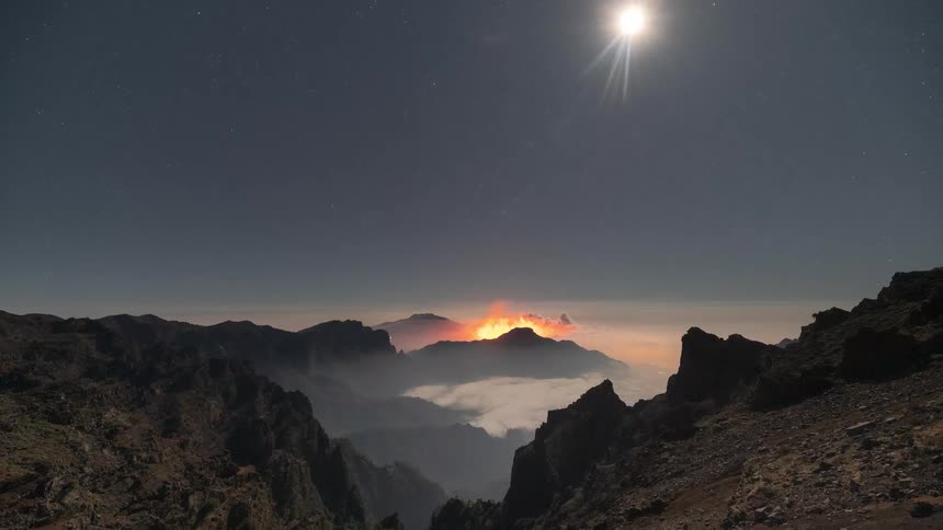 Epic night time-lapse of the Cumbre Vieja volcano erupting on La Palma under a bright moonlit, starry sky