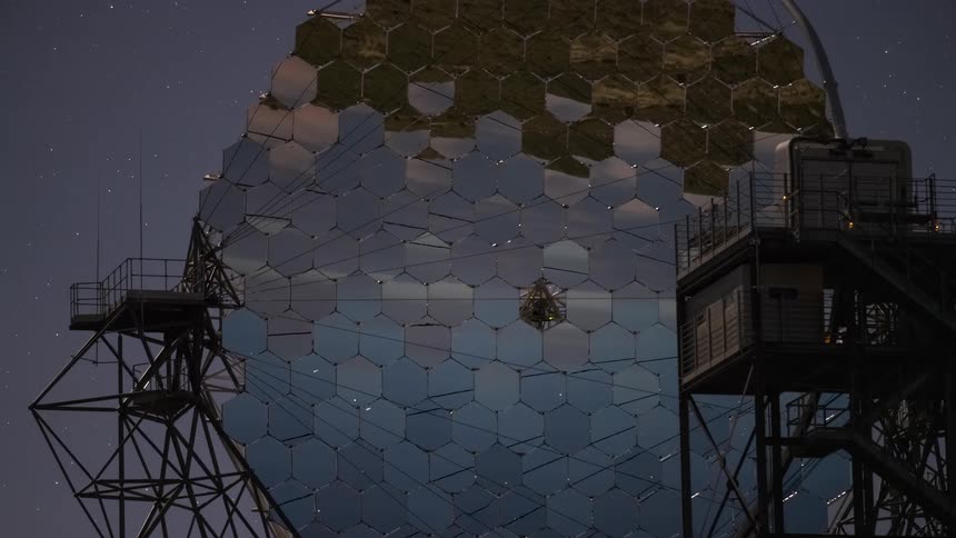 Day-to-night timelapse of a large hexagonal mirror array at an astronomical observatory reflecting the starry night sky