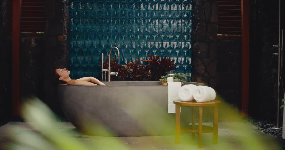 A beautiful woman relaxes and enjoys a luxurious bath in a modern outdoor spa