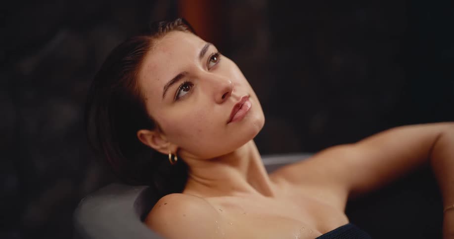 A beautiful young woman finds a moment of peace and tranquility while relaxing in a steamy hot tub