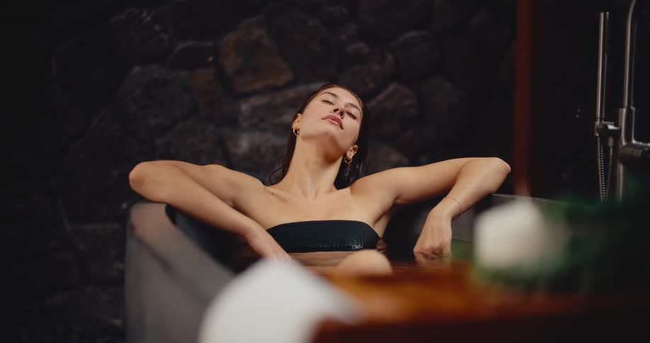 A tranquil young woman enjoys a relaxing soak in a luxurious, modern bathtub