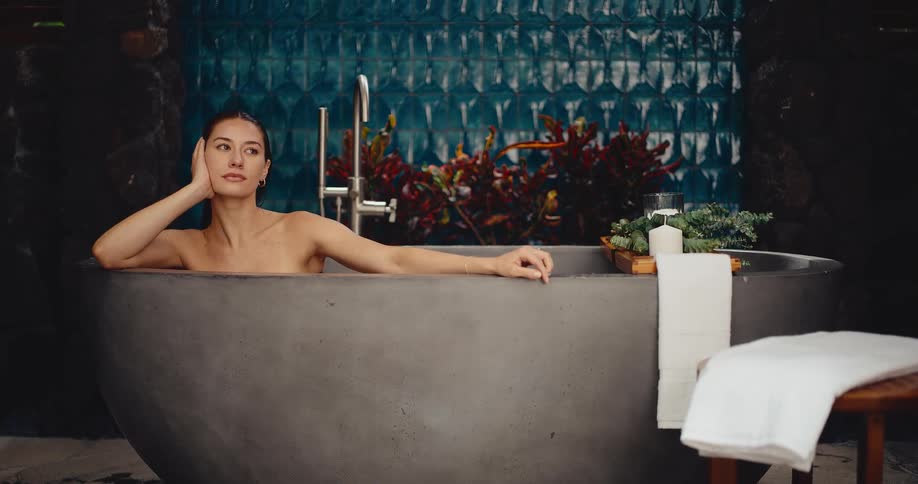 A serene woman finds tranquility as she relaxes in a luxurious modern stone bathtub at a day spa