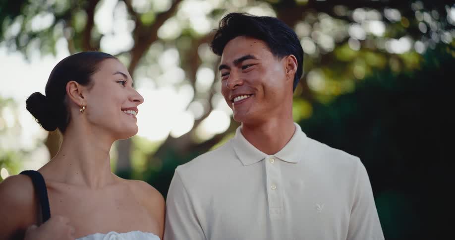 A happy young couple smiles and looks at each other lovingly while enjoying a beautiful day outdoors