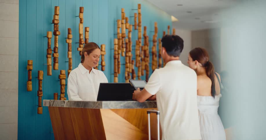 Couple on vacation checking in to a luxury hotel with a friendly receptionist at the front desk