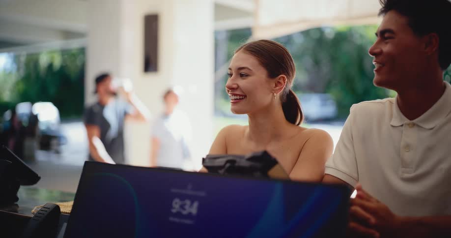 A happy young couple smiles and laughs while checking into a beautiful open-air resort