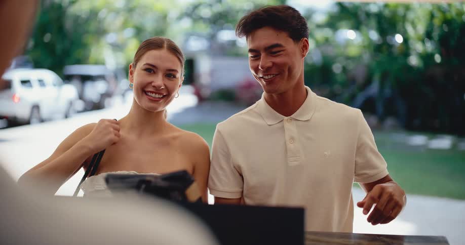 A happy young couple smiles as they check into a beautiful tropical resort for their vacation