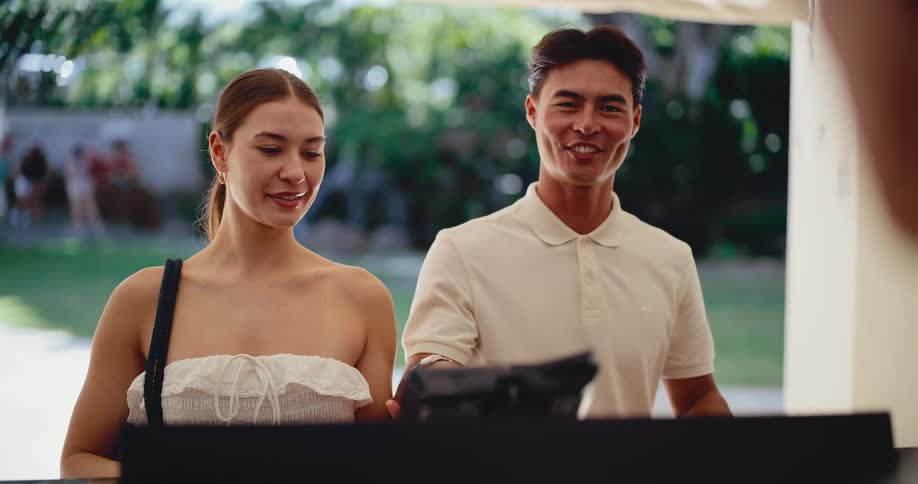 A happy young couple with luggage smiles as they check in at a tropical resort reception desk