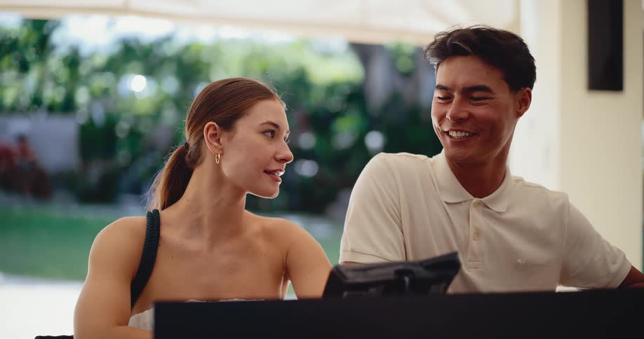 A happy young couple smiles and talks while standing at the reception desk of a beautiful tropical resort