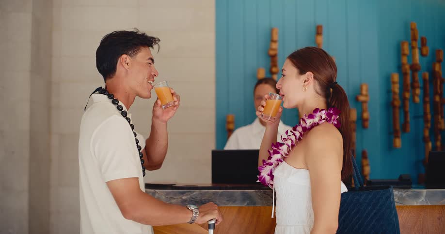 Happy couple on vacation checks into a luxury hotel resort, toasting with welcome drinks at the front desk