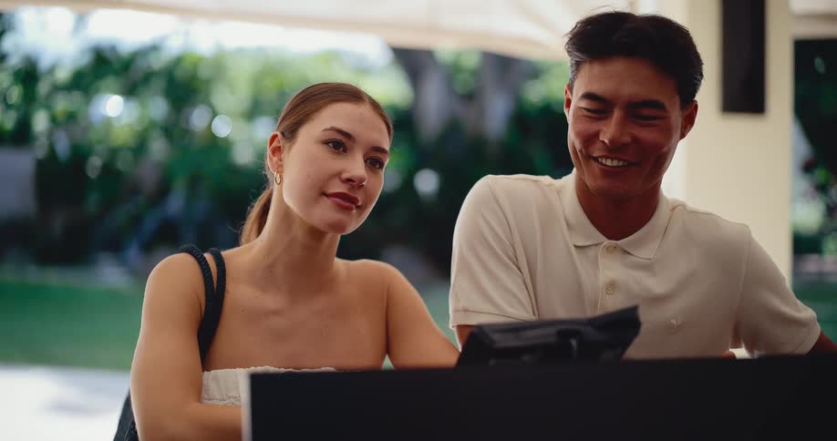 Over the shoulder view of a joyful couple arriving and checking into their luxury hotel for a vacation