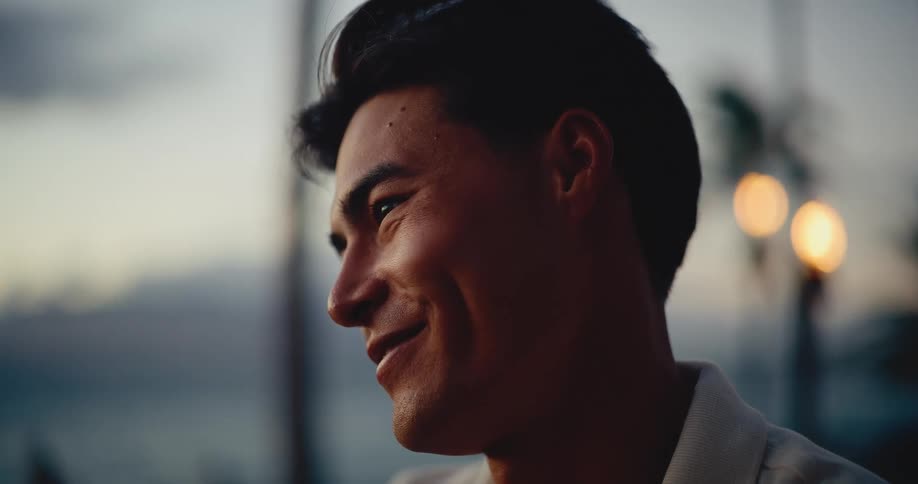 Slow motion close-up portrait of a handsome young man smiling at sunset