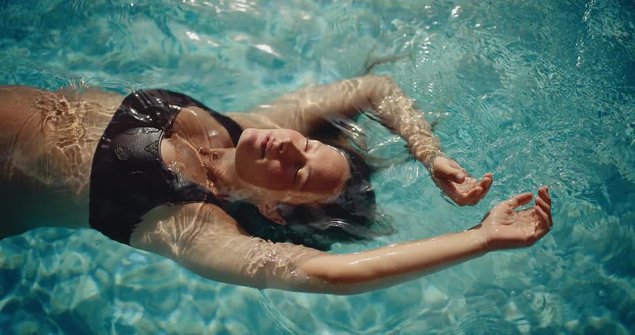Serene pregnant woman finds tranquility floating weightlessly in a sunlit swimming pool