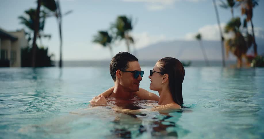 An attractive couple enjoys a romantic moment together in a beautiful infinity pool at a luxury resort