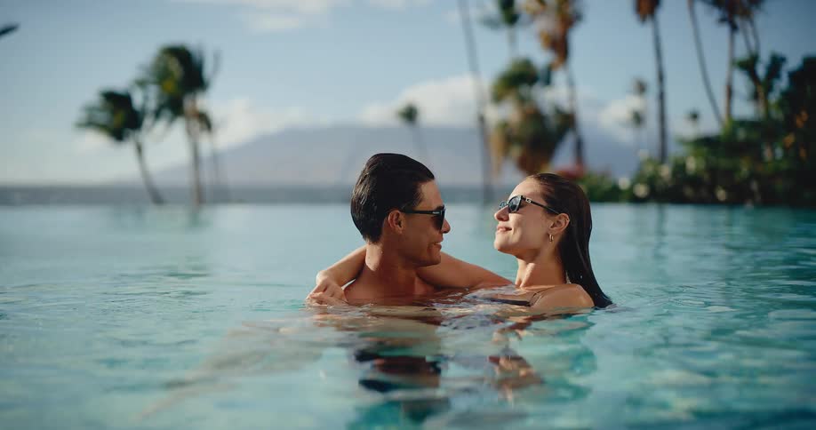 A loving couple enjoys a romantic moment together, embracing in a stunning infinity pool at a luxurious tropical resort