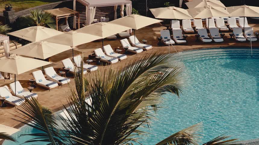A couple enjoys a relaxing vacation, sunbathing on in-water lounge chairs at a luxurious tropical resort pool