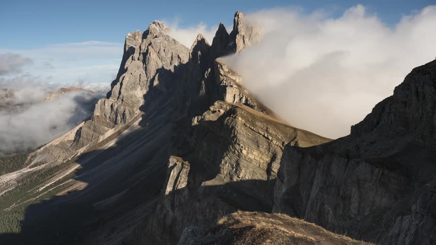 Epic view of the Seceda ridgeline in the Dolomites as clouds slowly drift over the rugged mountain peaks