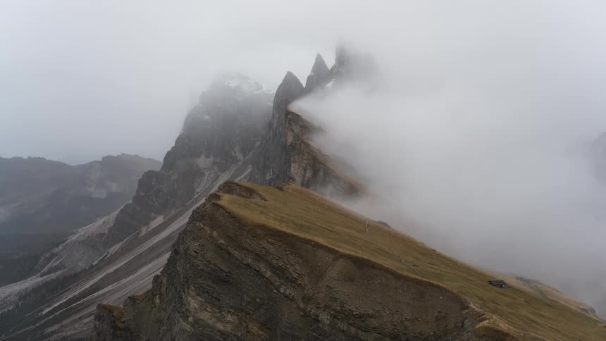 A stunning and moody view of a mountain ridge as thick fog and clouds roll over the jagged peaks